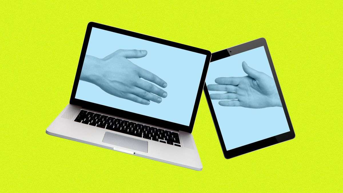 A handshake, with one hand on a laptop screen and the other on an iPad