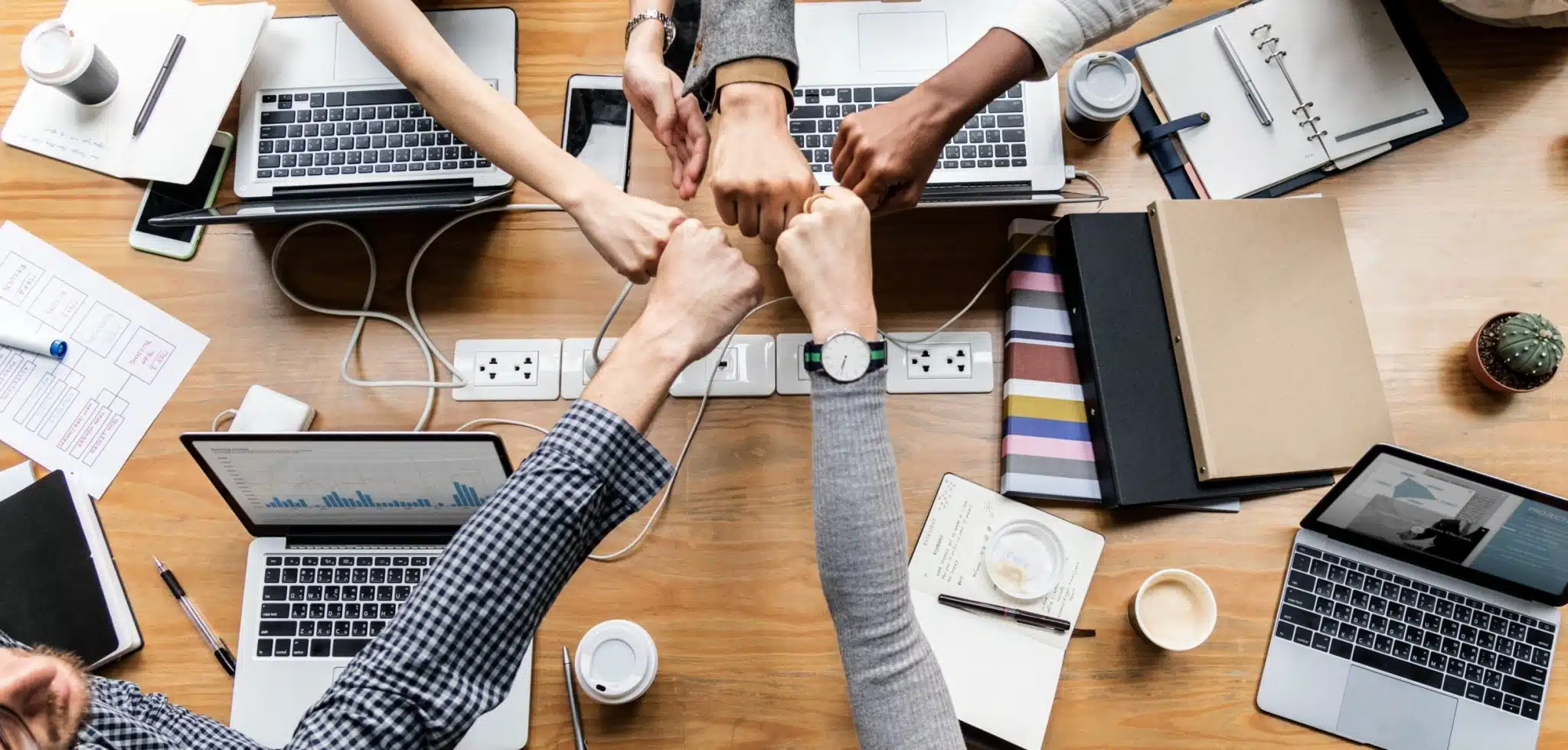 Hands fist-bumping over a work table